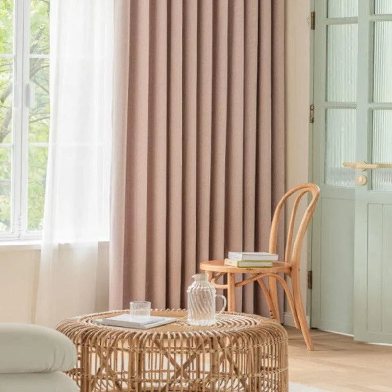 Rideau beige élégant pour salon, créant une ambiance chaleureuse et moderne. Parfait pour filtrer la lumière tout en ajoutant une touche décorative. Éléments naturels et mobilier en bois clair complètent cet espace accueillant. Solution idéale pour un intérieur contemporain et apaisant.