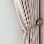 Rideau élégant beige clair attaché avec un embrasse en métal doré, idéale pour une décoration intérieure sophistiquée. Parfait pour apporter une touche de luxe et de fonctionnalité à tout salon ou chambre à coucher.