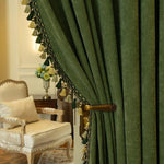 Rideaux élégants verts avec pompons, ajoutant une touche de sophistication à un salon classique. Le contraste entre le rideau vert et le fauteuil beige crée une ambiance chaleureuse et accueillante. Idéal pour une décoration intérieure chic et raffinée.