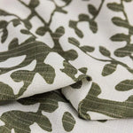 Tissu décoratif à motifs végétaux verts sur fond blanc, idéal pour la confection de rideaux ou d'ameublement. Design élégant et moderne pour un intérieur tendance.