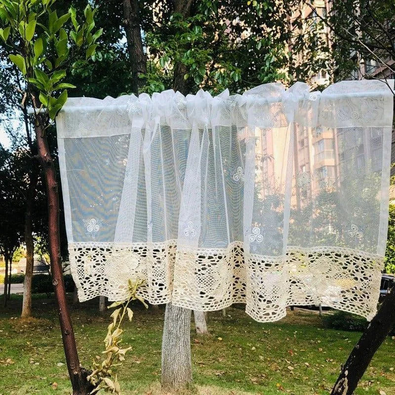 Petit rideau décoratif blanc suspendu en extérieur, idéal pour apporter une touche élégante et raffinée à une fenêtre. Design orné de motifs brodés et bordure en crochet, parfait pour une décoration intérieure charmante. Adapté aux espaces modernes comme classiques, ce rideau combine esthétique et fonctionnalité.