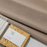 Image montrant des échantillons de design, avec un tissu beige en arrière-plan et des carnets de notes colorés plats. Parfait pour l'inspiration en décoration intérieure ou le choix de palettes de couleurs pour l'aménagement d'espace. Style moderne et élégant, idéal pour des projets créatifs ou tendances.