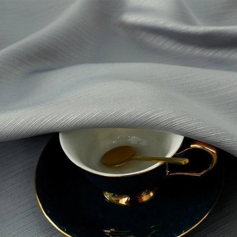 Tasse à café élégante avec soucoupe noire et dorée, partiellement recouverte par un textile lisse et raffiné. Cet ensemble de vaisselle ajoute une touche de sophistication à votre table, idéal pour les moments de répit et de dégustation de café. Accessoire chic pour les amateurs de design contemporain.