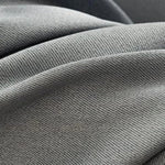Plan serré sur un tissu gris avec un tissage serré, idéal pour la décoration intérieure et les projets de couture. Découvrez la texture élégante et les nuances subtiles de ce matériau d'ameublement polyvalent.