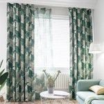 Rideaux à motif tropical vert et blanc égayant un salon moderne. Ces tentures ajoutent une touche de fraîcheur et d'élégance à la pièce, complétant un décor contemporain avec une lampe originale et un canapé confortable, tout en assurant un bel apport de lumière naturelle. Idéal pour créer une ambiance apaisante et chaleureuse dans votre intérieur.