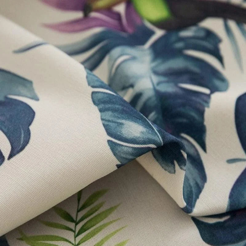 Tissu imprimé avec motif tropical, feuilles exotiques bleu et vert, idéal pour décoration intérieure estivale, rideaux élégants et accessoires de maison tendance. Motif jungle chic pour renouveler votre intérieur avec style et fraîcheur.