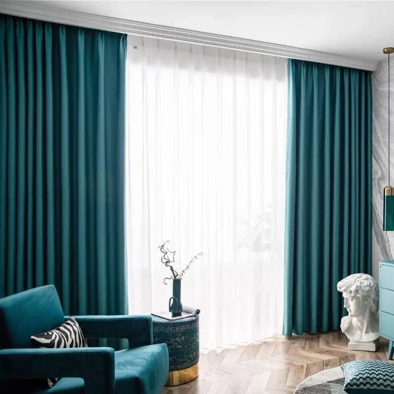 Rideaux élégants bleu canard pour salon moderne, offrant un contraste esthétique avec des voilages blancs pour une ambiance lumineuse. Décoration intérieure raffinée avec fauteuil assorti, table d'appoint décorative et sculpture artistique. Améliorez votre espace avec ces éléments de design chic et contemporain.
