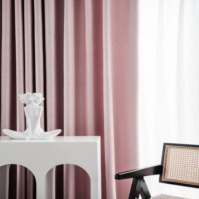 Rideaux élégants rose doux, ajoutant une touche de sophistication à votre intérieur. Statue minimaliste blanche sur une table moderne avec une chaise design à accoudoirs en bois foncé et assise en cannage. Idéal pour un salon chic et contemporain.