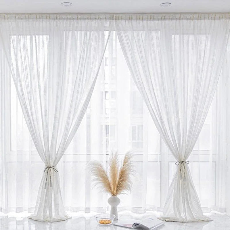 Rideaux translucides blancs élégants pour salon moderne, idéal pour laisser entrer la lumière naturelle tout en préservant l'intimité. Design contemporain avec attaches décoratives, parfaits pour créer une ambiance lumineuse et apaisante dans votre espace de vie. Accessoire déco indispensable pour rehausser le style de votre intérieur.