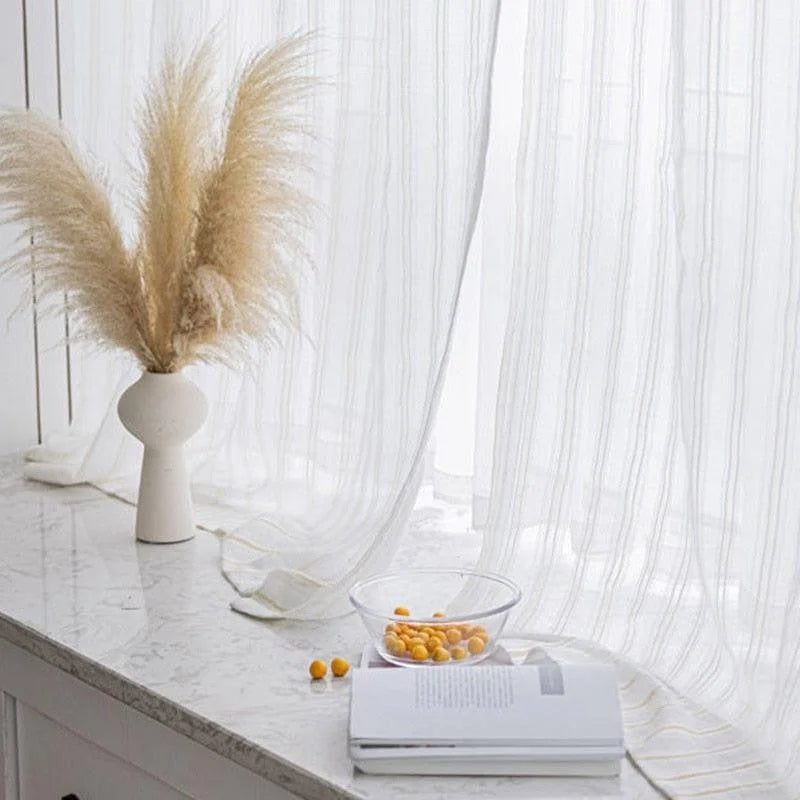 Vase décoratif minimaliste avec herbes pampas naturelles sur un rebord de fenêtre lumineux, aux côtés de rideaux élégants et d'une table en marbre. Transformez votre intérieur avec cet accent moderne et épuré qui s’intègre parfaitement dans un salon ou une chambre. Idéal pour apporter une touche de sophistication et de naturel à votre espace de vie.