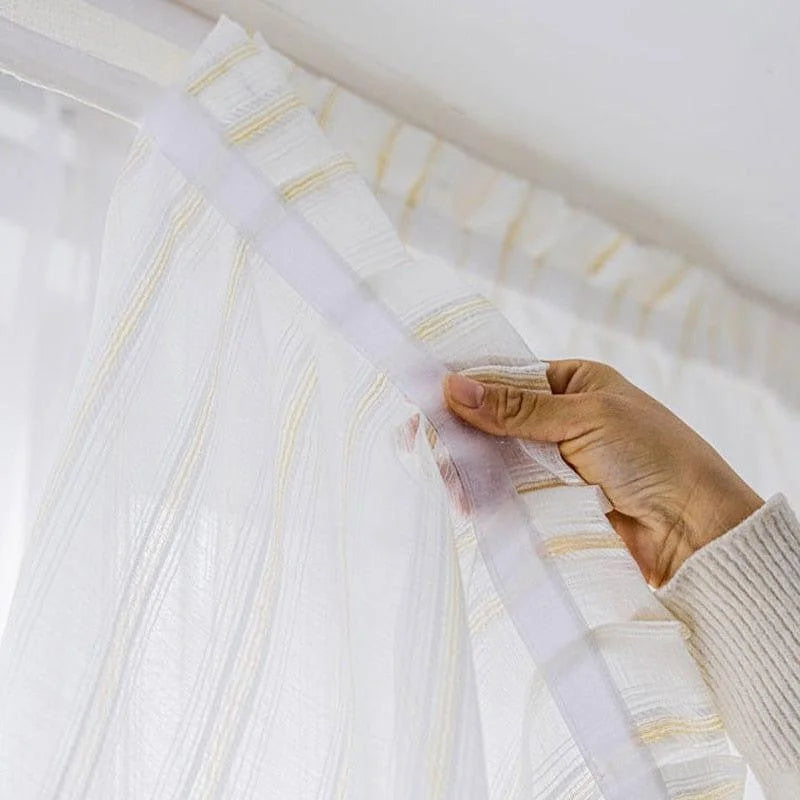 Voilage transparent doté de fines rayures verticales, idéal pour illuminer une pièce tout en préservant l'intimité. Facile à accrocher grâce à son système de fixation pratique, il s'adapte parfaitement aux tringles modernes. Parfait pour embellir les fenêtres du salon ou de la chambre.