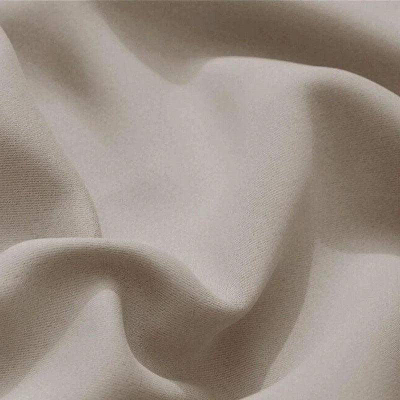 Gros plan sur un tissu élégant, présentant des plis doux dans une teinte beige naturelle. Ce textile raffiné évoque le confort et le style, idéal pour la décoration d'intérieur ou la confection de vêtements tendance.