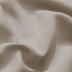 Gros plan sur un tissu élégant, présentant des plis doux dans une teinte beige naturelle. Ce textile raffiné évoque le confort et le style, idéal pour la décoration d'intérieur ou la confection de vêtements tendance.