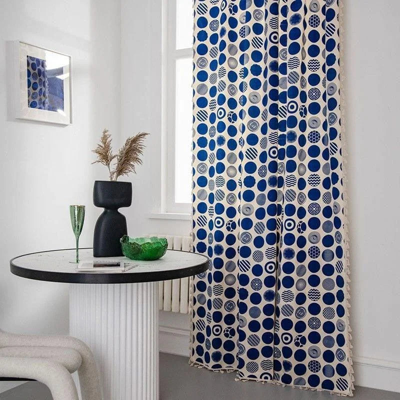 Rideau moderne à motifs circulaires bleus dans un intérieur élégant. Ce rideau apporte une touche contemporaine et artistique à votre pièce, s'associant parfaitement avec des décorations de table design. Parfait pour ceux qui cherchent à ajouter du style et de la couleur à leur espace de vie.