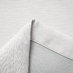 Gros plan sur un revêtement mural blanc aux motifs modernes texturés, idéal pour une décoration intérieure élégante. Parfait pour apporter une touche contemporaine et raffinée à n'importe quelle pièce.