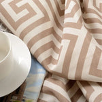 Tissu beige avec motifs géométriques, idéal pour la décoration intérieure moderne, accompagné d'une tasse à café blanche et d'un magazine. Parfait pour apporter une touche contemporaine à votre espace de vie.