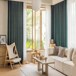 Salon moderne avec un canapé beige confortable et des rideaux verts élégants, accentué par une chaise design en bois et un éclairage naturel grâce à de grandes fenêtres. Le salon offre une ambiance chaleureuse et accueillante, idéale pour la détente et la convivialité. Découvrez comment transformer votre intérieur avec ces éléments de décoration tendance.