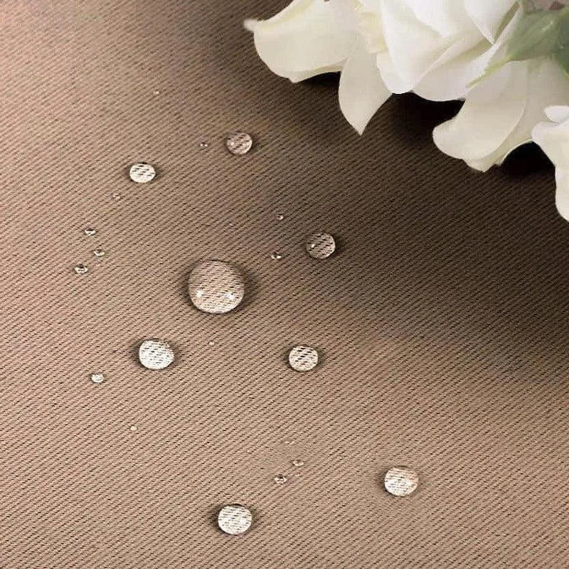 Gouttelettes d'eau sur une surface résistante, démontrant l'imperméabilité et la durabilité du tissu, avec des fleurs blanches en arrière-plan pour sublimer l'élégance du décor.
