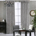 Rideaux élégants gris à motifs géométriques suspendus dans un salon contemporain, complétant la décoration intérieure avec des chaises modernes et une horloge murale design, pour une ambiance chic et confortable.