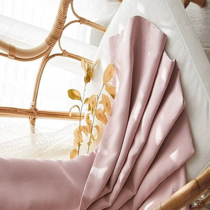 Voilage élégant de couleur rose pâle, drapé délicatement sur une chaise en rotin, décoré de feuilles séchées dorées, idéal pour ajouter une touche de sophistication et naturel à votre intérieur.