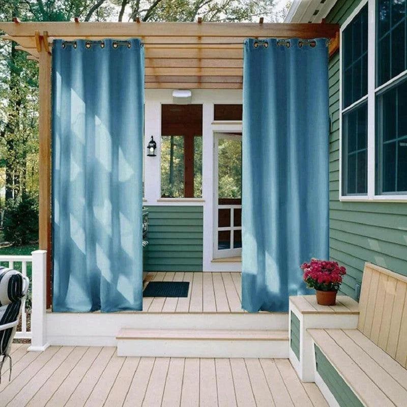Rideaux d'extérieur bleus suspendus sur une terrasse, offrant intimité et style à l'espace extérieur, parfaits pour embellir jardins et vérandas.