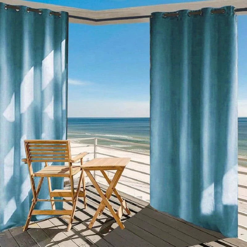 Rideaux bleus élégants pour terrasse, parfaits pour filtrer la lumière du soleil tout en profitant de la vue sur la mer. Ces rideaux contemporains ajoutent une touche esthétique à votre espace extérieur, offrant intimité et confort. Aménagement idéal pour une ambiance relaxante en plein air.