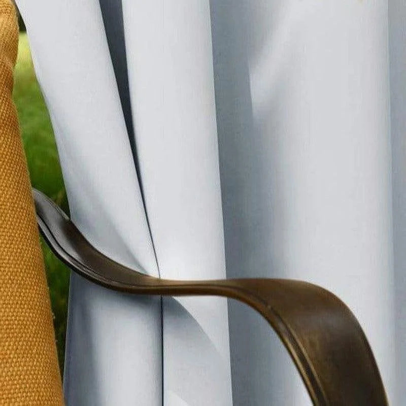 Attache-rideaux en métal doré élégamment conçu, accompagné de rideaux blancs et d'un élément décoratif jaune. Accessoire de maison sophistiqué, idéal pour la décoration intérieure moderne.