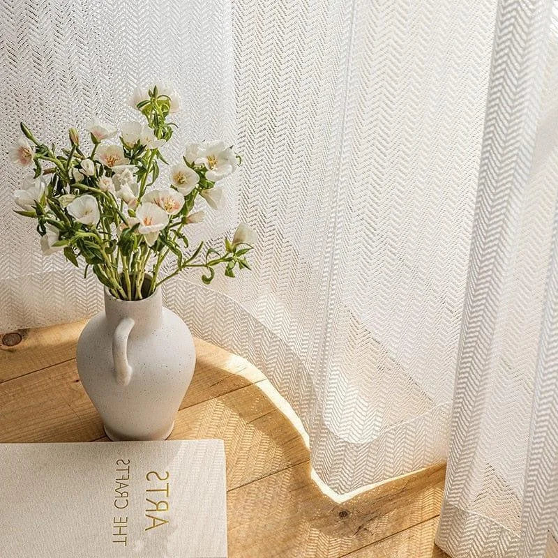 Vase décoratif blanc avec bouquet de fleurs blanches sur une table en bois, placé à côté d'un rideau lumineux, créant une ambiance élégante et apaisante dans la pièce. Accessoire idéal pour sublimer votre intérieur avec une touche florale naturelle.