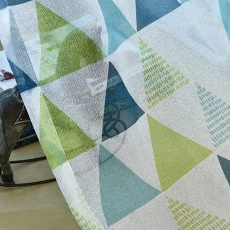 Image d'un tissu aux motifs géométriques colorés en vert et bleu, idéal pour apporter une touche moderne à votre intérieur. Design contemporain parfait pour décoration de maison, rideaux ou accessoires textiles tendance.