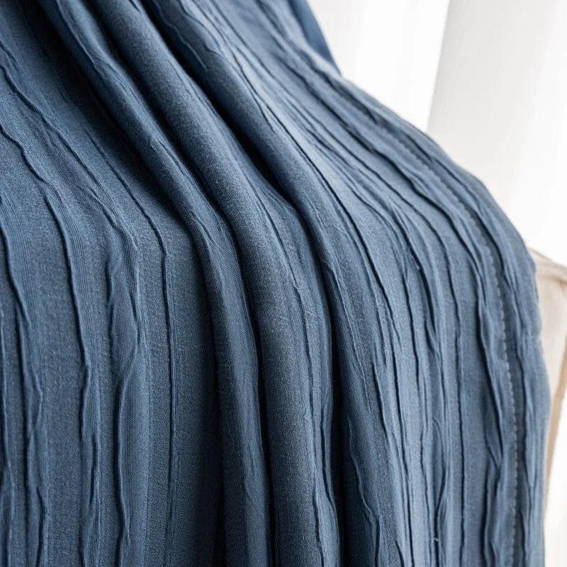 Étoffe bleue texturée drapée sur une surface claire, idéale pour la décoration intérieure raffinée et contemporaine.