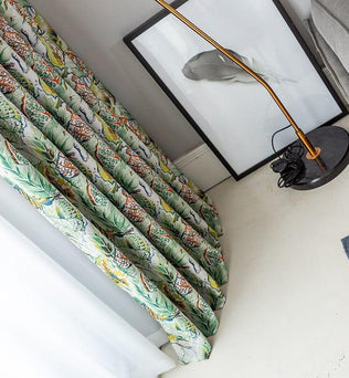 Rideau coloré avec motifs tropicaux dans un intérieur moderne, accompagné d'un cadre décoratif et d'une lampe élégante. Accessoire parfait pour ajouter une touche exotique et lumineuse à votre décoration intérieure.