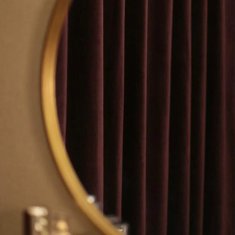 Miroir rond au cadre doré devant un rideau sombre, idéal pour une décoration élégante et moderne. Parfait pour ajouter une touche sophistiquée à votre intérieur.