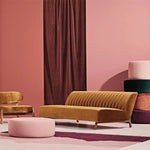 Salon moderne avec canapé jaune moutarde, chaise assortie et pouf rose dans un décor élégant avec rideaux bordeaux et murs roses, créant une ambiance chaleureuse et accueillante. Mobilier design pour un intérieur contemporain et chic.
