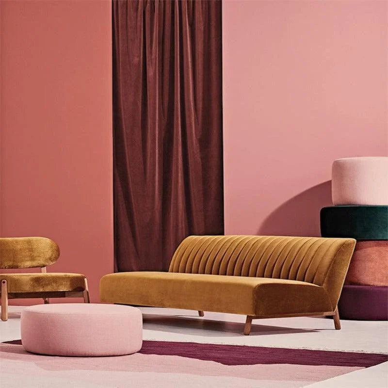 Salon moderne avec canapé jaune moutarde, chaise assortie et pouf rose dans un décor élégant avec rideaux bordeaux et murs roses, créant une ambiance chaleureuse et accueillante. Mobilier design pour un intérieur contemporain et chic.