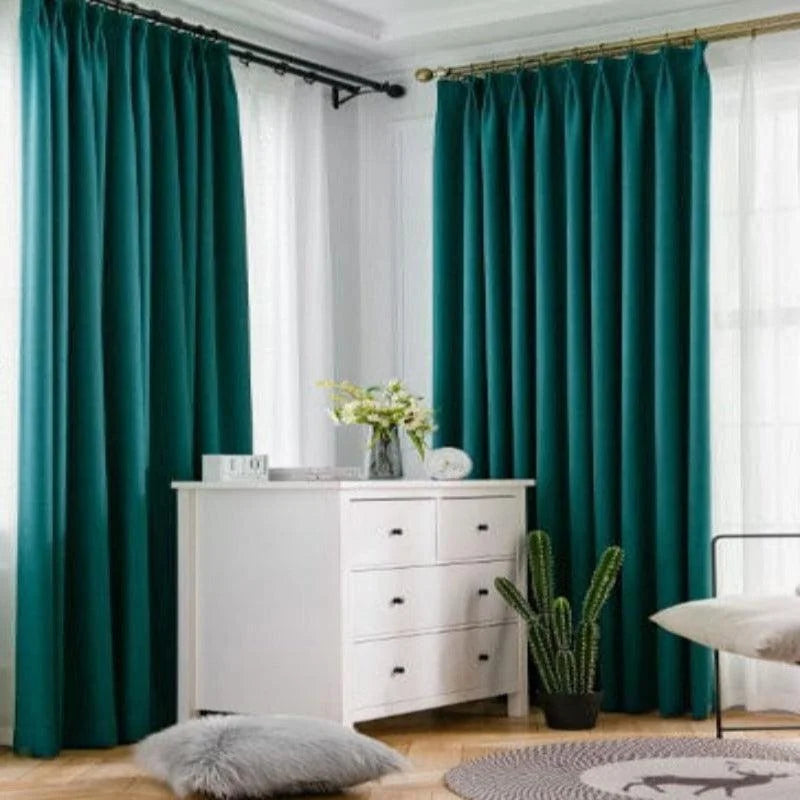 Rideaux opaques élégants de couleur turquoise dans un salon moderne avec une décoration minimaliste, mettant en avant une commode blanche et des accents naturels tels qu'un cactus et des fleurs fraîchement coupées, offrant une ambiance apaisante et contemporaine.