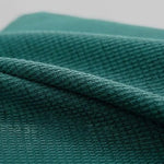 Tissu vert texturé plié, gros plan montrant les détails et le motif du textile. Parfait pour confection textile et projets créatifs, offre un aspect sophistiqué et tendance.