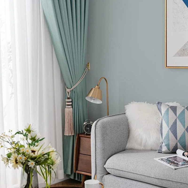 Salon moderne avec rideaux verts élégants, lampe dorée design, canapé gris confortable et coussin géométrique décoratif. Parfait pour un intérieur chic et contemporain. Décoration de maison avec des fleurs fraîches pour une ambiance naturelle et chaleureuse.
