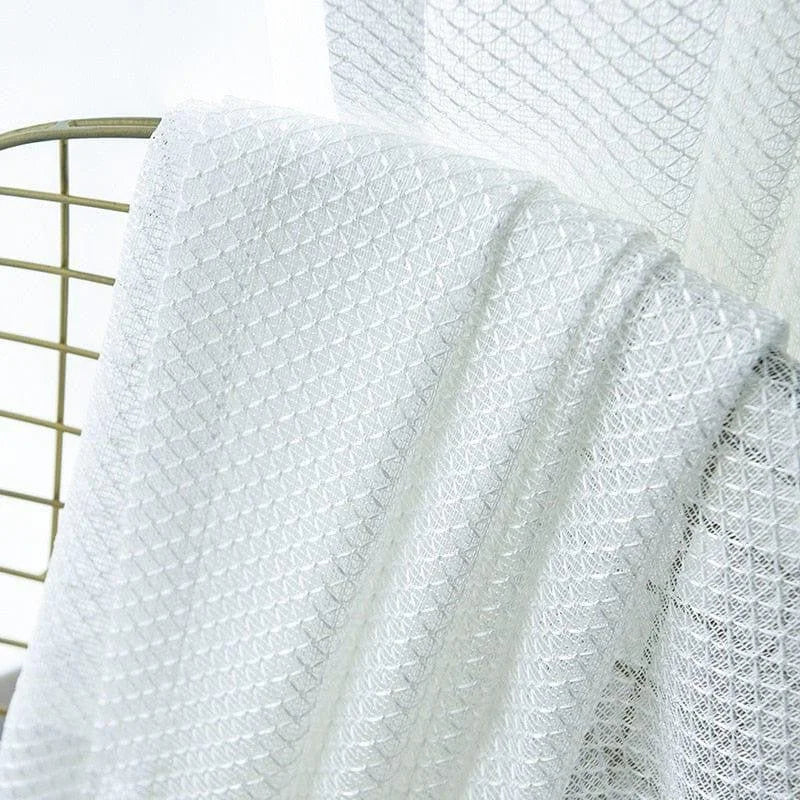 Voilage blanc avec motif géométrique sur chaise, idéal pour une décoration intérieure élégante et lumineuse. Parfait pour laisser passer la lumière tout en préservant l'intimité. Ambiance moderne et épurée.