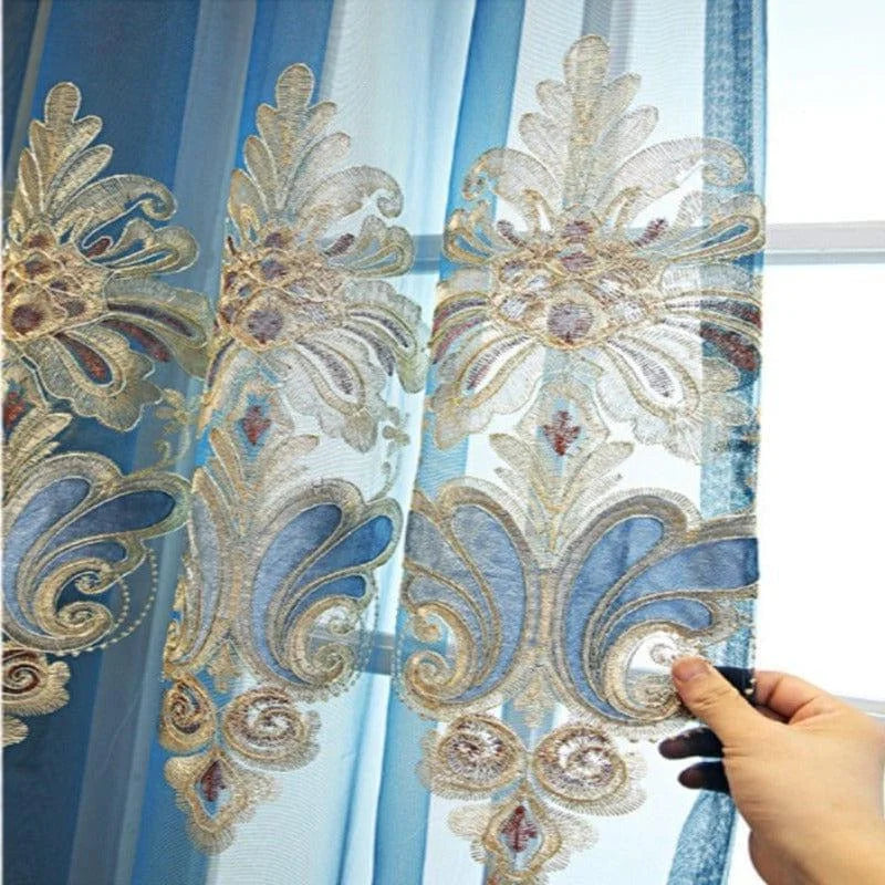 Rideau de luxe bleu avec motifs brodés dorés pour salon élégant, apportant une touche sophistiquée à la décoration intérieure. Design floral détaillé, idéal pour embellir vos fenêtres tout en filtrant délicatement la lumière naturelle. Parfait pour une décoration chic et contemporaine.