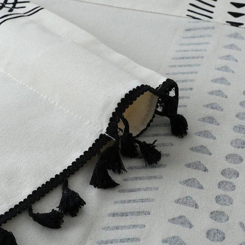 Gros plan d'un rideau décoratif avec un motif géométrique élégant et des franges noires pour une touche de style bohème. Idéal pour ajouter du caractère à votre intérieur tout en filtrant la lumière avec une touche artistique.