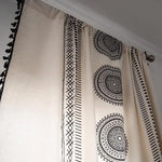 Rideau design avec motifs ethniques noirs et blancs, idéal pour décorer un salon moderne ou une chambre à coucher. Ce modèle original de rideau offre une touche d'élégance et de style, grâce à ses motifs géométriques circulaires et ses bordures détaillées. Parfait pour ajouter une ambiance chaleureuse et contemporaine à votre intérieur.