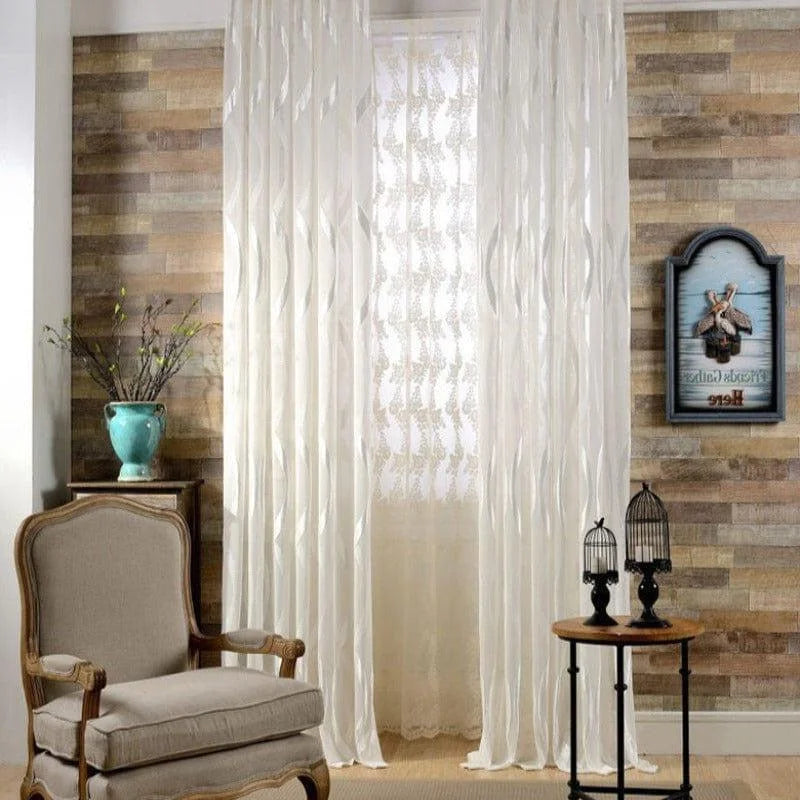 Décor élégante pour salon avec rideaux. Ambiance raffinée avec fauteuil classique, mur en bois moderne, vase décoratif bleu, et petites cages à oiseaux sur table. Idéal pour offrir une touche sophistiquée et chaleureuse à votre intérieur.