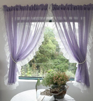 Rideaux décoratifs violets à franges blanches, élégamment attachés avec une corde ornée de perles. Ces rideaux apportent une touche de charme romantique à votre intérieur tout en laissant passer la lumière. Parfaits pour une ambiance apaisante dans un salon ou une chambre avec vue sur un jardin verdoyant.