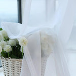 Voilage blanc élégant drapé autour d'un panier de fleurs blanches, idéal pour ajouter une touche de douceur et de romantisme à votre intérieur. Parfait pour décorer un salon lumineux ou une chambre apaisante, créant une atmosphère sereine et rafraîchissante.