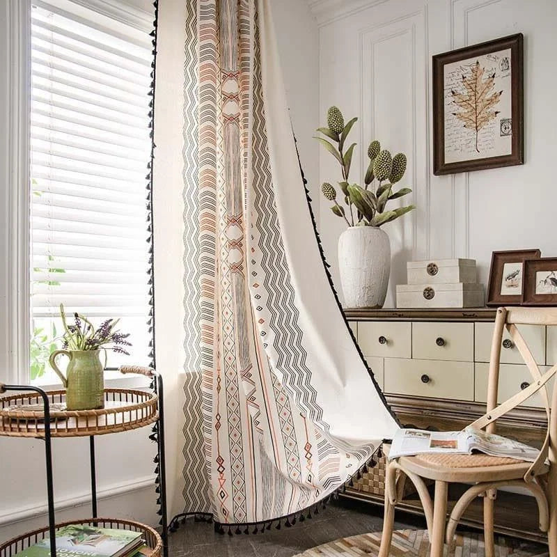 Rideau avec motifs géométriques colorés suspendu dans un salon lumineux, créant une ambiance bohème et élégante. Le design unique et les couleurs chaleureuses ajoutent une touche de style et d'originalité à l'espace, complétée par un mobilier en bois et des éléments de décoration naturelle. Idéal pour personnaliser et raviver votre intérieur.