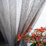 Rideau scintillant avec motifs délicats et détails brillants, accompagné de branches de fruits rouges décoratifs. Élégance et style pour la décoration intérieure.
