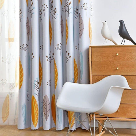 Rideaux modernes avec motif naturel de feuilles et fleurs, parfaits pour ajouter une touche de couleur et de nature à votre salon. La pièce est complétée par une chaise blanche au design épuré et une commode en bois clair, offrant une ambiance élégante et paisible. Idéal pour les intérieurs contemporains à la recherche d'une décoration rafraîchissante et tendance.