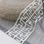 Gros plan sur un tissu décoratif aux motifs géométriques entrelacés, idéal pour rehausser l'esthétique intérieure et ajouter une touche de sophistication à tout espace.