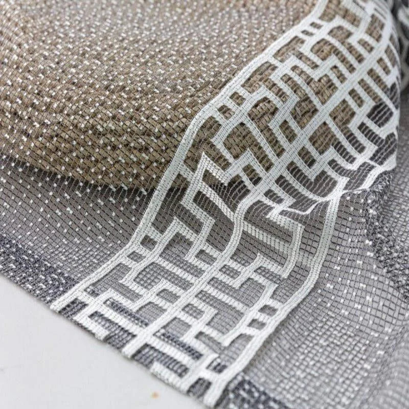 Gros plan sur un tissu décoratif aux motifs géométriques entrelacés, idéal pour rehausser l'esthétique intérieure et ajouter une touche de sophistication à tout espace.