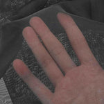 Main en gros plan touchant un tissu fin et transparent, illustrant la légèreté et la texture délicate du produit idéal pour la confection de vêtements, doublures ou accessoires.